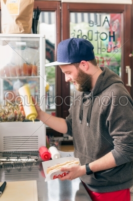 salesman making hotdog in fast food snack bar