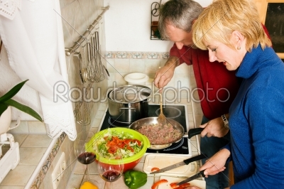 Senior couple cooking dishes in kitchen