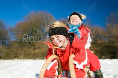 Sisters in snow on toboggan