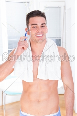 smiling man shaving face with razor