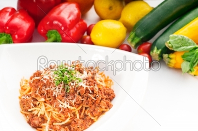 spaghetti with bolognese sauce and fresh vegetables on backgroun