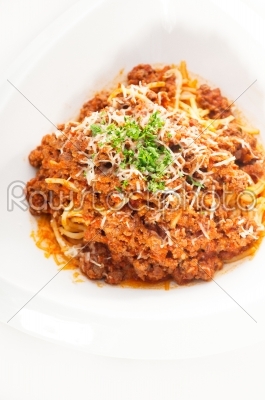 spaghetti with bolognese sauce and fresh vegetables on backgroun