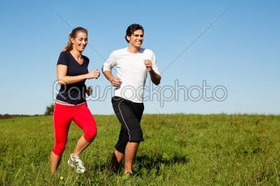 sport couple jogging an meadow in summer