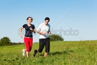 sport couple jogging an meadow in summer