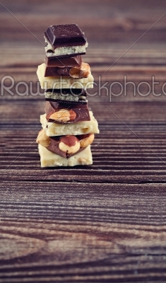 Stack of white, dark and milk chocolates on wooden table