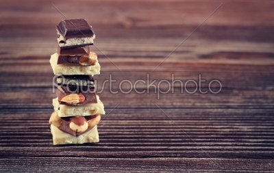 Stack of white, dark and milk chocolates on wooden table
