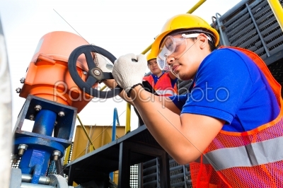 Technicians working on valve in factory or utility