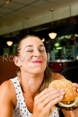 Woman in a restaurant eating hamburger