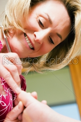 Woman practicing chiropody taking care of a feet; focus on face