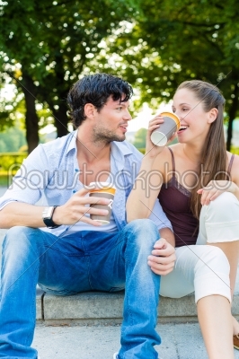 Young couple in city park drinking coffee