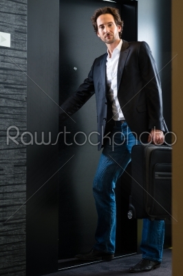 Young guest with luggage entering hotel room