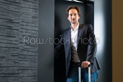 Young guest with luggage entering hotel room
