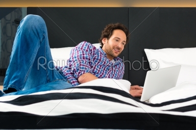Young man in Hotel in bed with wifi and computer