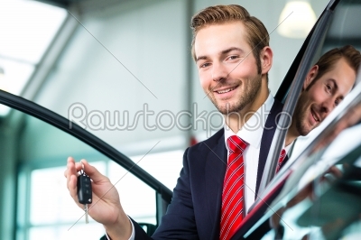 Young man or auto dealer in car dealership
