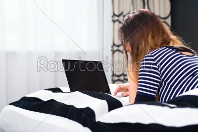 Young woman in Hotel in bed with wifi and computer